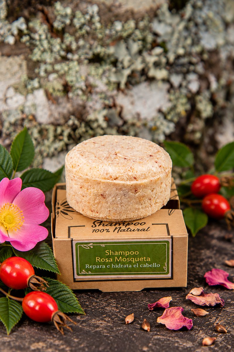 Shampoo sólido de rosa mosqueta sobre su caja kraft, junto a flores y frutos de rosa mosqueta