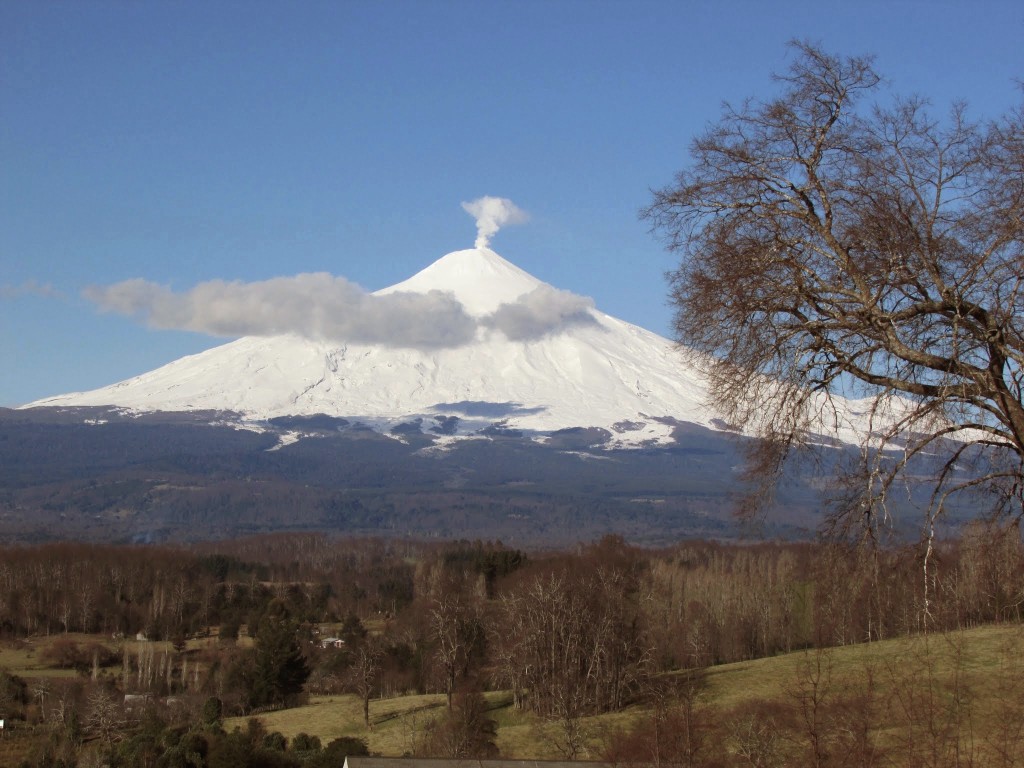 Volcán Villarrica nevado entre bosques y campos de la Araucanía